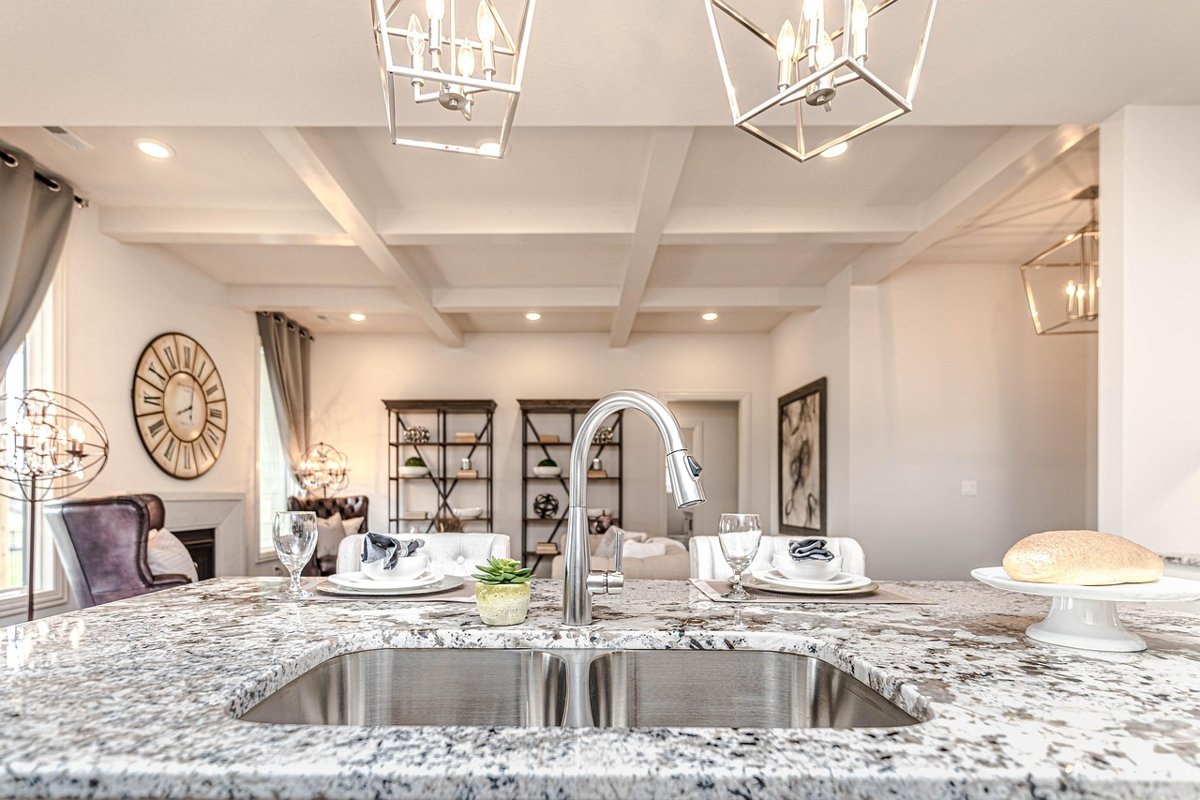 Kitchen island with a speckled stone countertop, undermount sink and pendant lights above